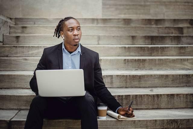 An African American man taking notes and listening to headphones